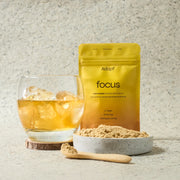 Adapt Lion's Mane Powder Powder packaging - vibrant yellow with focus written on the front. A glass with Adapt Focus next to it.
